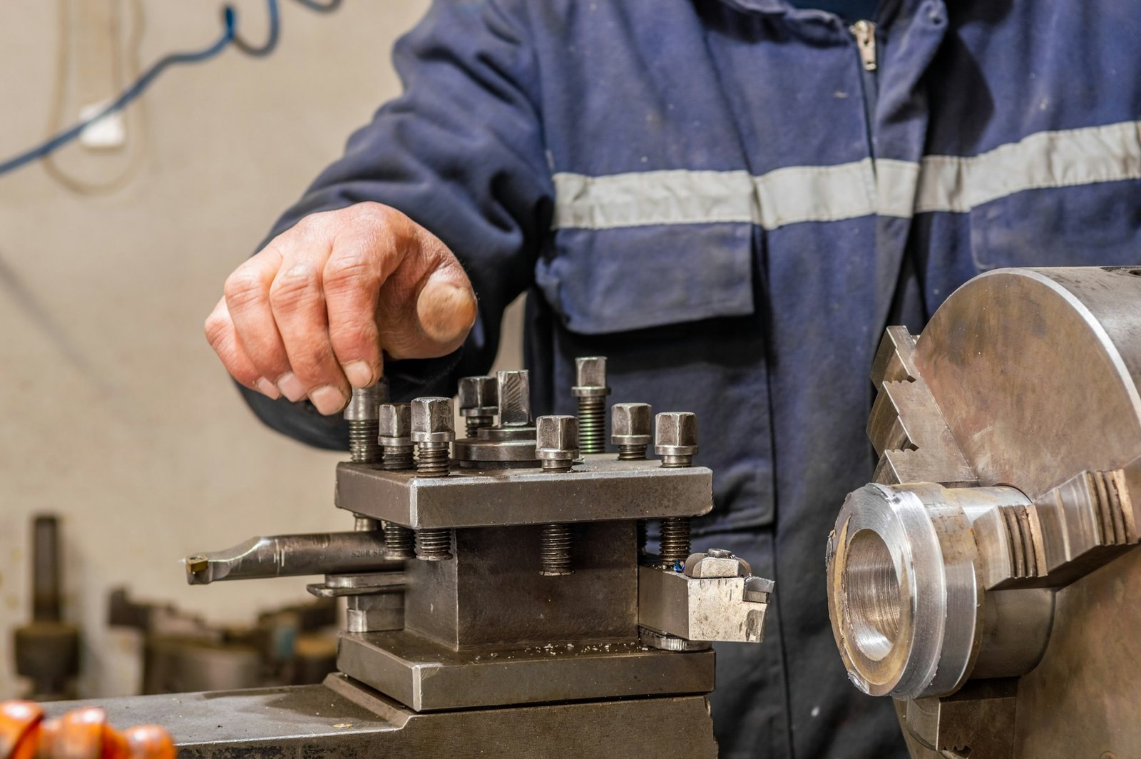 Blue-collar machine operator working with lathe machine in a factory.