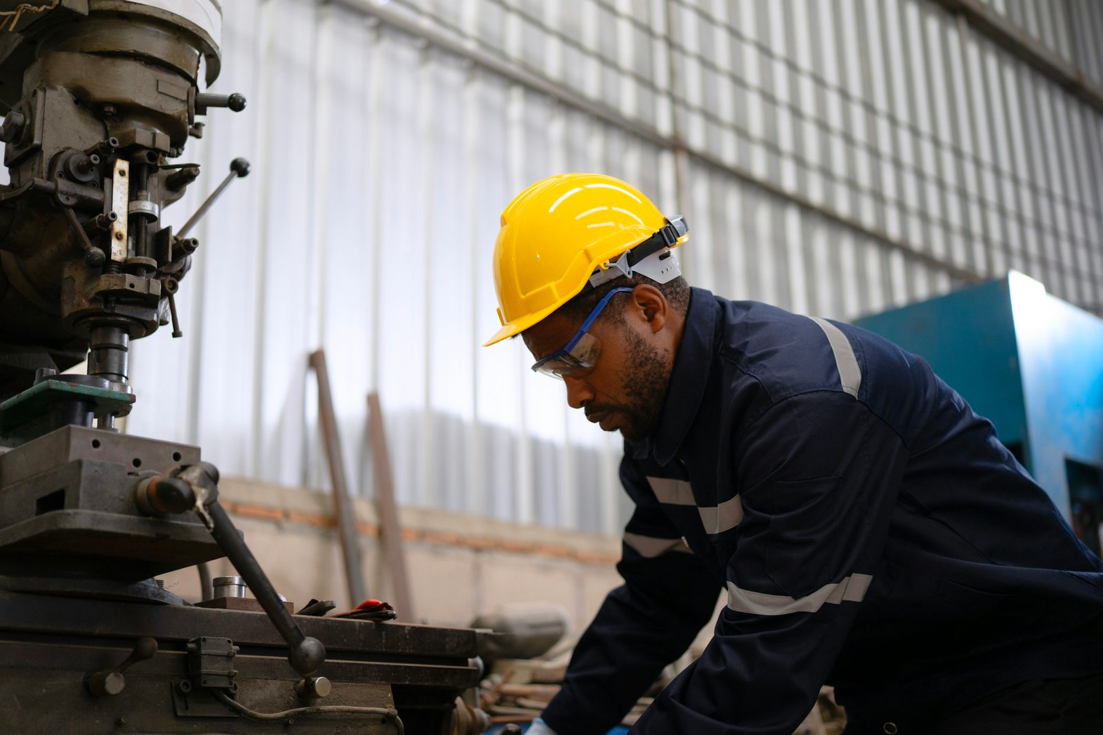 Blue collar workers at machine shop with welding robot arm.